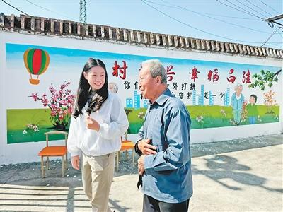 图为卢玫（左）在和村民交流。