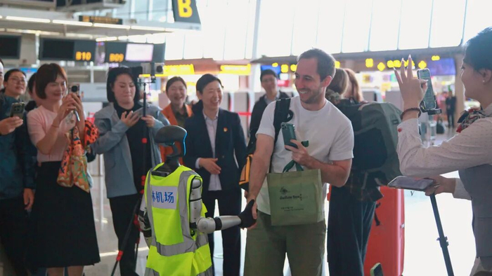 身穿桂林机场马甲的机器人与一名外国旅客友好握手。通讯员阳艳  摄