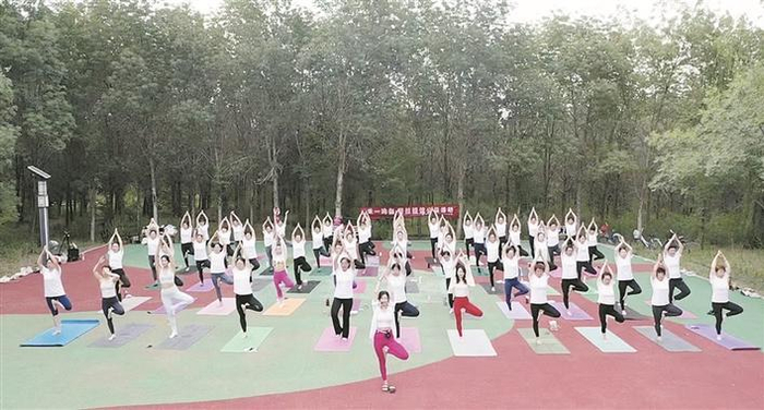 六师五家渠市禾一瑜伽普拉提馆的瑜伽教练带领学员们在户外做瑜伽（资料图片）。段飓风 摄