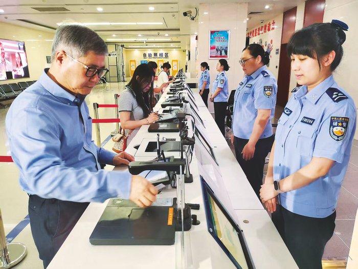 在南宁市公安局出入境管理支队办证大厅，罗浩夫（左一）申请办理往来港澳人才签注。记者 朱新韬 摄