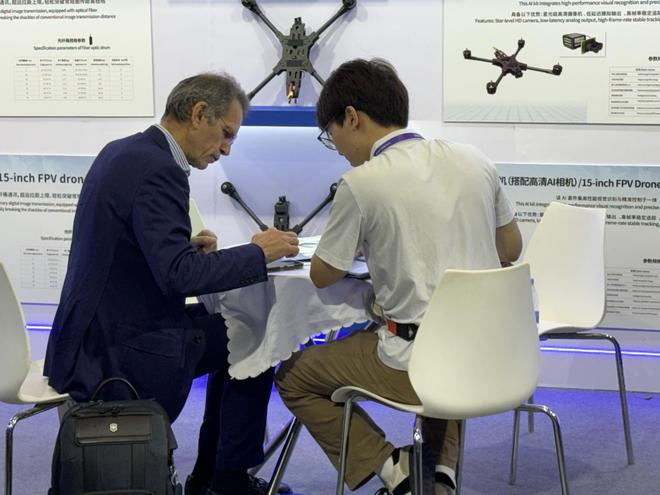 图：外国采购商与参展企业的工作人员咨询 来源：每经记者 黄婉银 摄