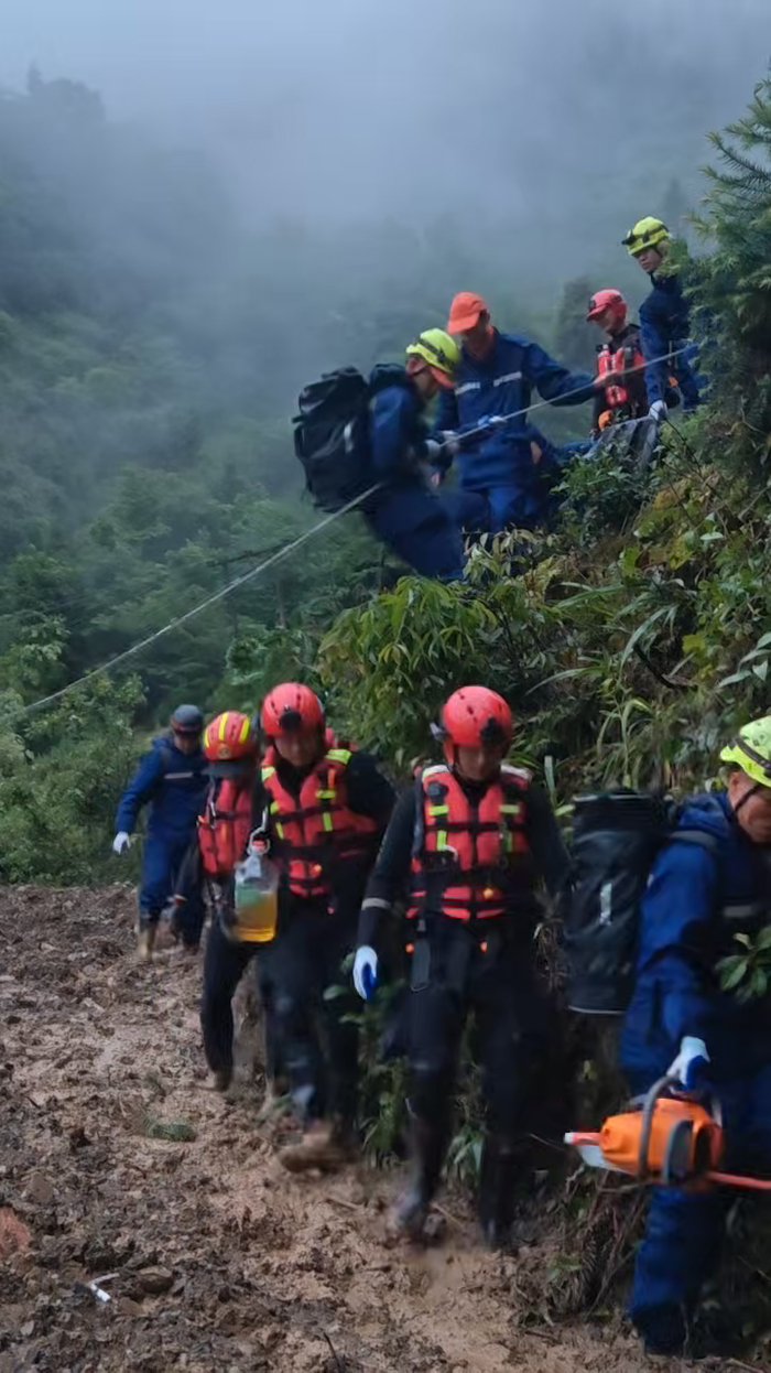 ▲洪水过后的山路泥泞坎坷，救援人员使用绳索辅助前进。图源：湖南省应急管理厅公号