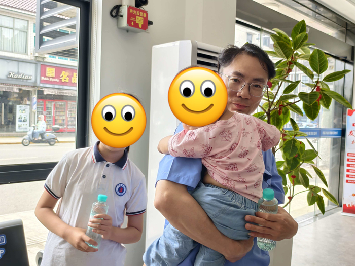 “钓鱼侠”刘胜抱起被救女童，旁边是女童的姐姐