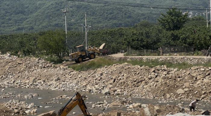5月12日，下港镇开山村附近石汶河河道，一辆铲车将盗采的大型泰山石运往村委会方向。 新京报记者 齐少乾 摄