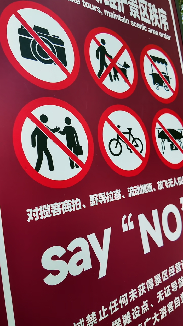 放置在西湖边的告示牌，提醒游客防范违规揽客商拍