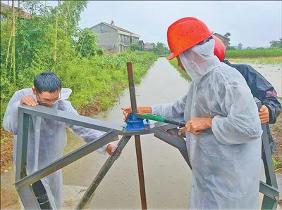 图为澧县工作人员操作水闸，为稻田紧急排水。