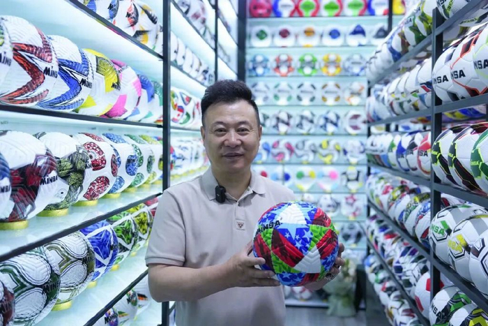 陈绍美展示自主设计生产的热销足球。图片来源：新华社
