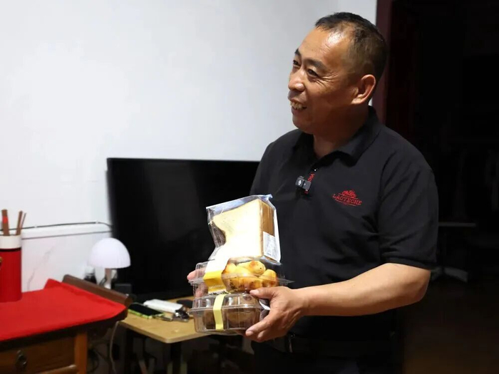 5月18日，在河南商丘永城市的家中，苏小锋将在杭州买的面包送给妻子。