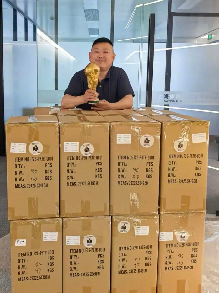 熊小锋与自家公司的大力神杯复制品合影。受访者供图