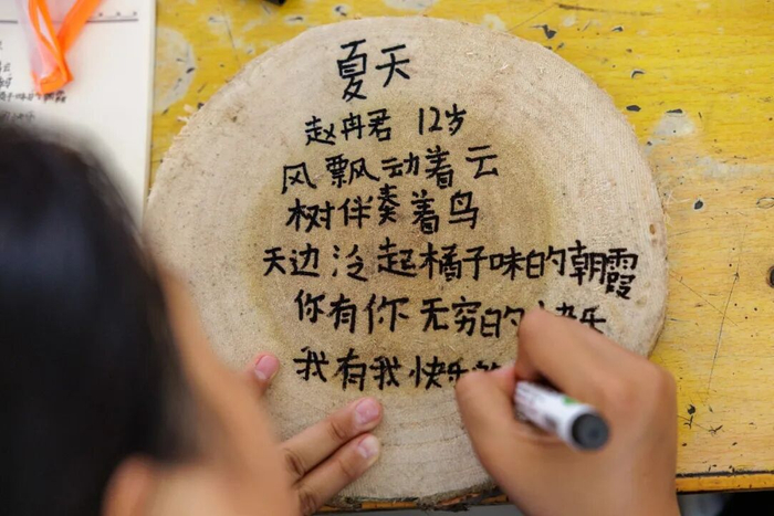 ▲5月13日，乡土教室里，孩子将诗歌写在圆木片上。新京报记者 王子诚 摄