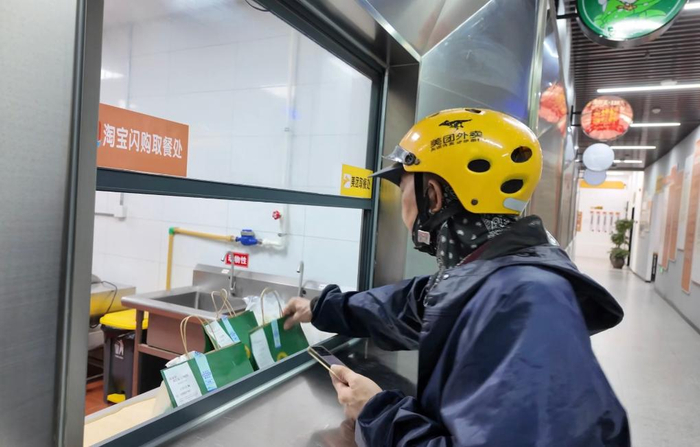 一名外卖骑手正在餐饮档口取餐。（受访者供图）