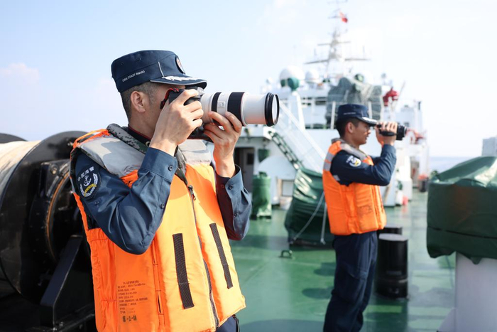 5月20日，海警执法员张继祥（左）在川山舰甲板上开展执法取证工作。新华社记者 陈斌 摄