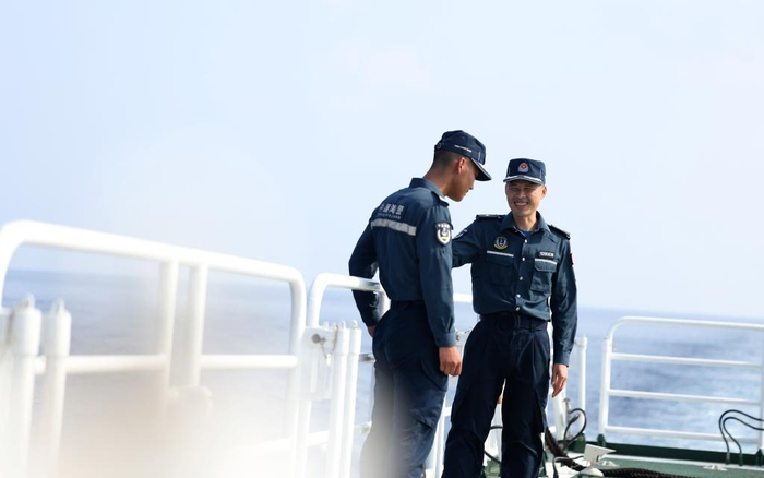 5月20日，海警执法员张继祥（右）和王鑫在川山舰甲板上交流。新华社记者 陈斌 摄