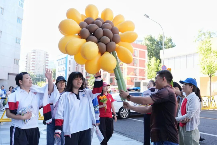 6月7日，在北京市陈经纶中学考点外，送考老师手拿向日葵花饰品为考生送上祝福。