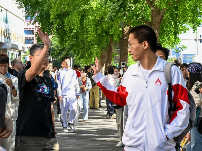 6月7日，在北京中国人民大学附属中学考点，一名考生走向考场时向送考的家长挥手。