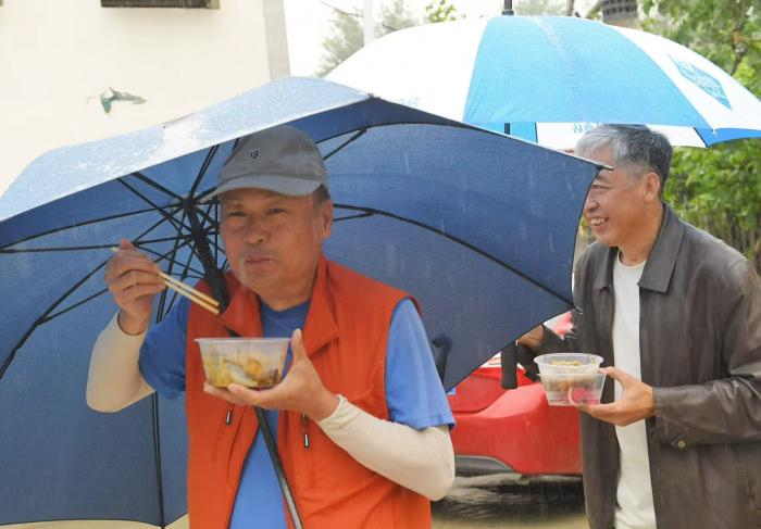 游客雨中撑伞品尝美食