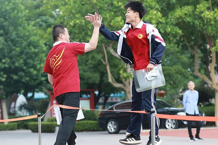 2026年6月7日，在山东省高密市第五中学考点，一名考生与老师击掌加油。