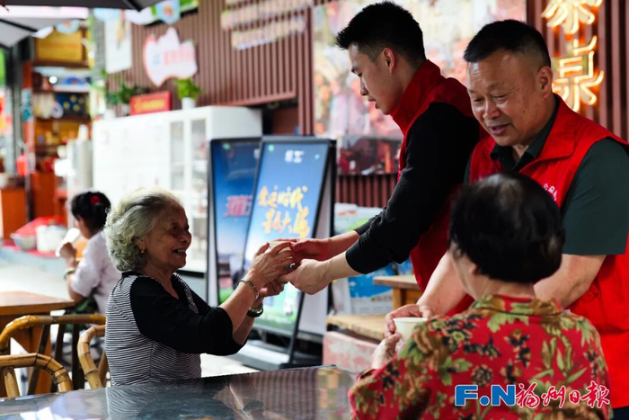 叶小弟（右一）、叶伟涛为游客送上爱心饮品。赖志昌 摄