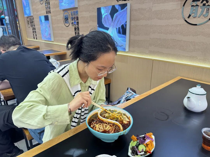 顾客正在食用一半三细、一半薄宽的“鸳鸯牛肉面”