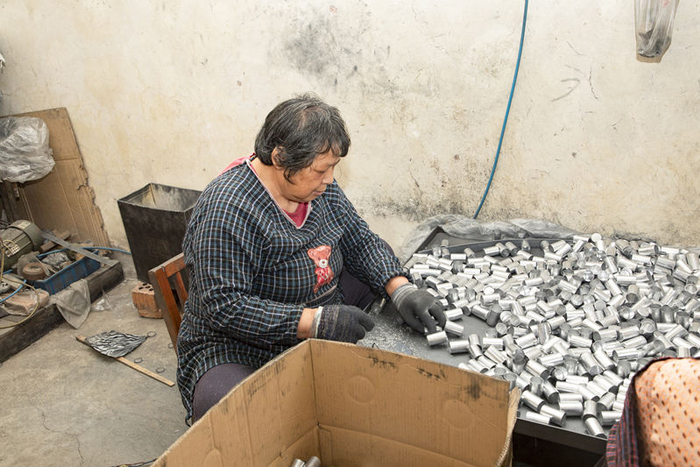 任金凤在家中分拣打磨从工厂带回的零件，计件获酬，补贴家用。 江阴市委宣传部供图
