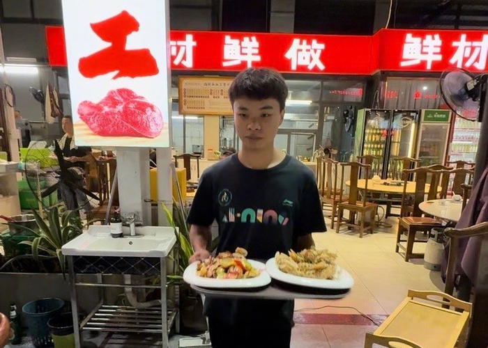 在三亚市火车头万人海鲜广场，服务人员将加工好的海鲜端上餐桌。海南日报全媒体记者 王程龙 摄