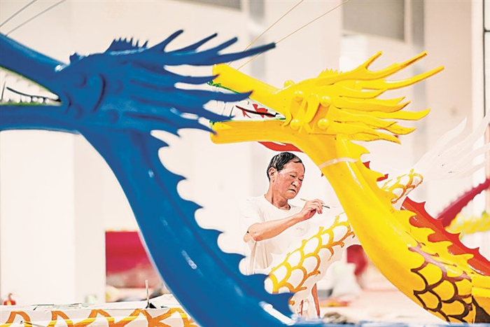 湖北宜昌市级非遗项目龙舟制作技艺代表性传承人郑祥龙在为龙舟进行彩绘。