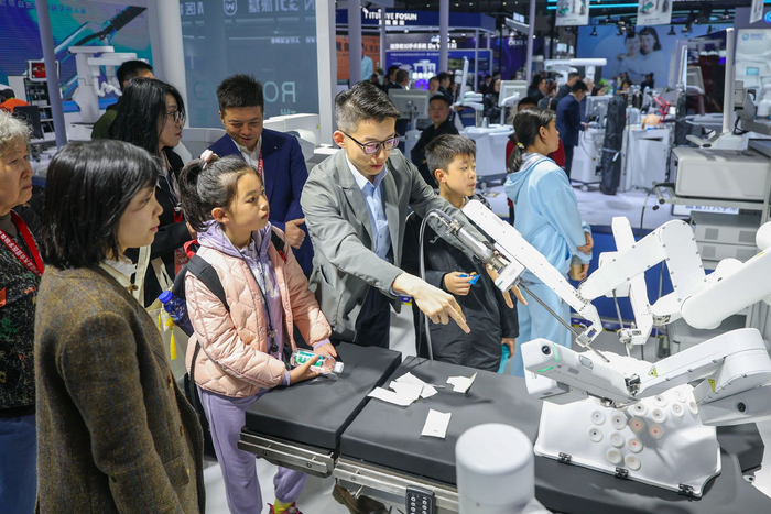 图为2026中国医学装备展览会现场，工作人员在为观众讲解分体式手术机器人工作原理。记者　黄伟　摄