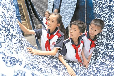 近日，江苏省南通市理治小学的学生在通州区二甲镇正兴染坊内了解蓝印花布制作工艺。 图片来源：视觉中国