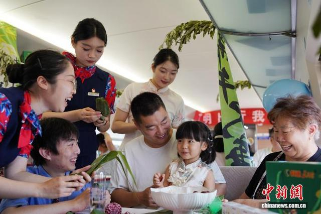 图为乘务员与旅客们一起包粽子。米思齐 摄 
