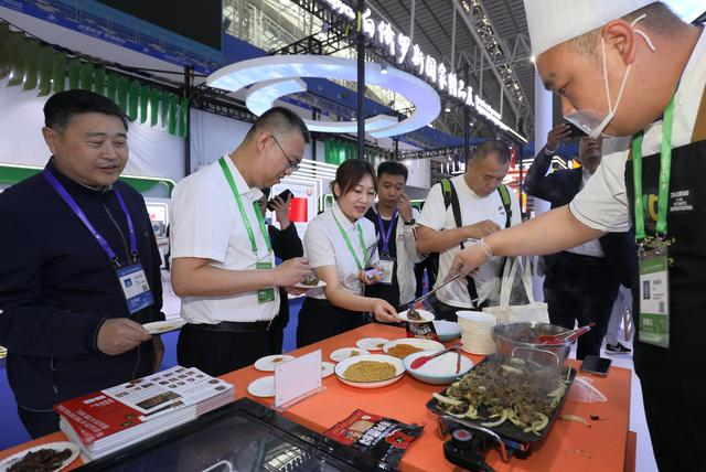 参会者在第十届中国—俄罗斯博览会齐齐哈尔展区品尝烤肉。 新华社发（张树/摄）