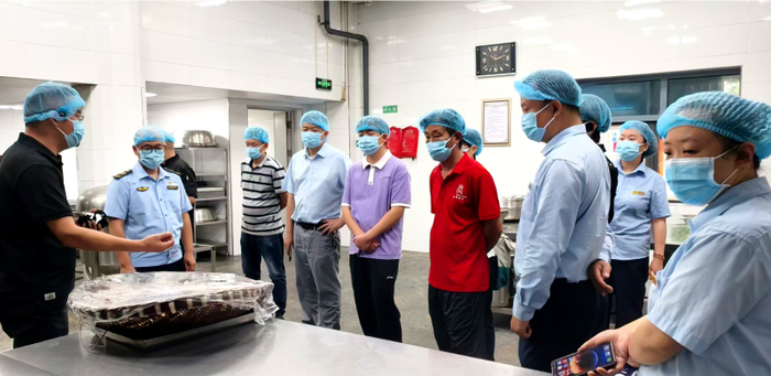 涪陵二中学校食堂管理人员向参观学习人员交流食材加工区后厨管理经验。