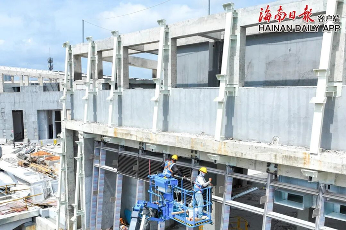6月19日，位于三亚市海棠湾的三亚国际免税城三期项目施工现场，工人们在忙着安装幕墙。 王程龙 摄