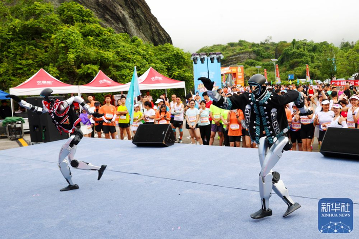 ↑ 6月20日，在重庆市黔江区小南海景区，机器人在一项跑步活动现场表演。新华社发（杨敏摄）