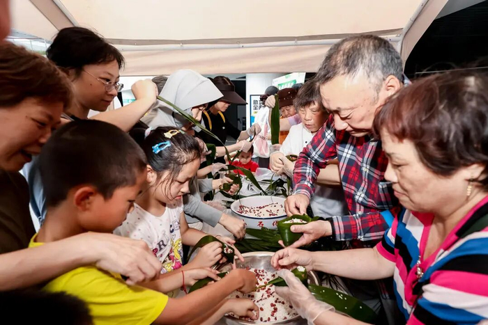 市民在桃浦端午游园会活动包粽子