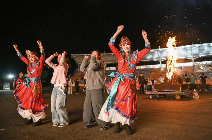 ↑6月17日，在丰宁满族自治县坝上一处景区，游客与演员一起体验篝火晚会。新华社发（王立群摄）