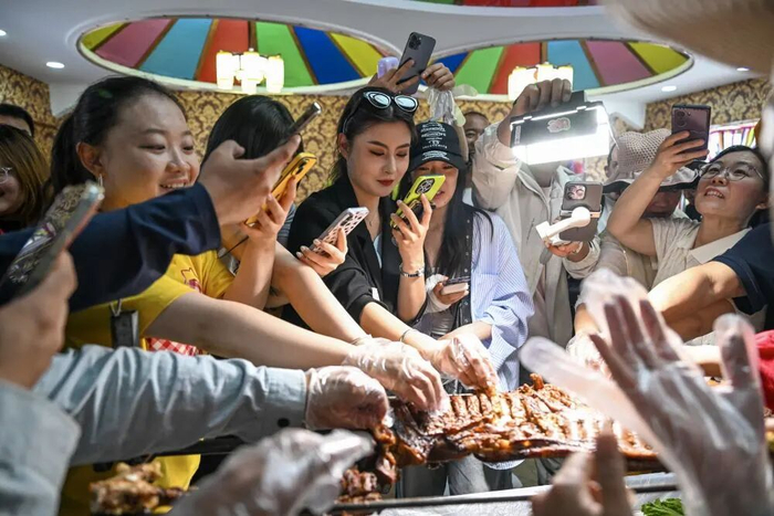↑6月17日，在丰宁满族自治县坝上一处景区，游客体验“采摘式”烤全羊。新华社发（王立群摄）