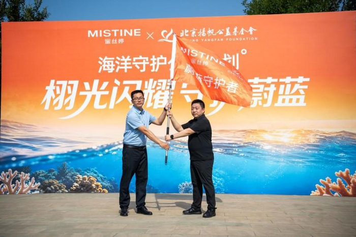 图说：北京扬帆公益基金会 执行理事长 王中与蓬莱仙境爱心志愿者协会会长 张希鑫 交接队旗
