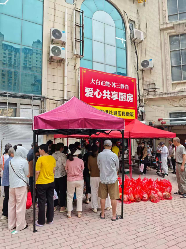 图为患者家属排队领取共享厨房免费提供的大锅菜