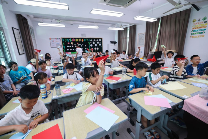  2026年7月9日，孩子们在浙江诸暨东白湖镇斯民小学教室里学习制作纸飞机。新华社记者 徐昱 摄