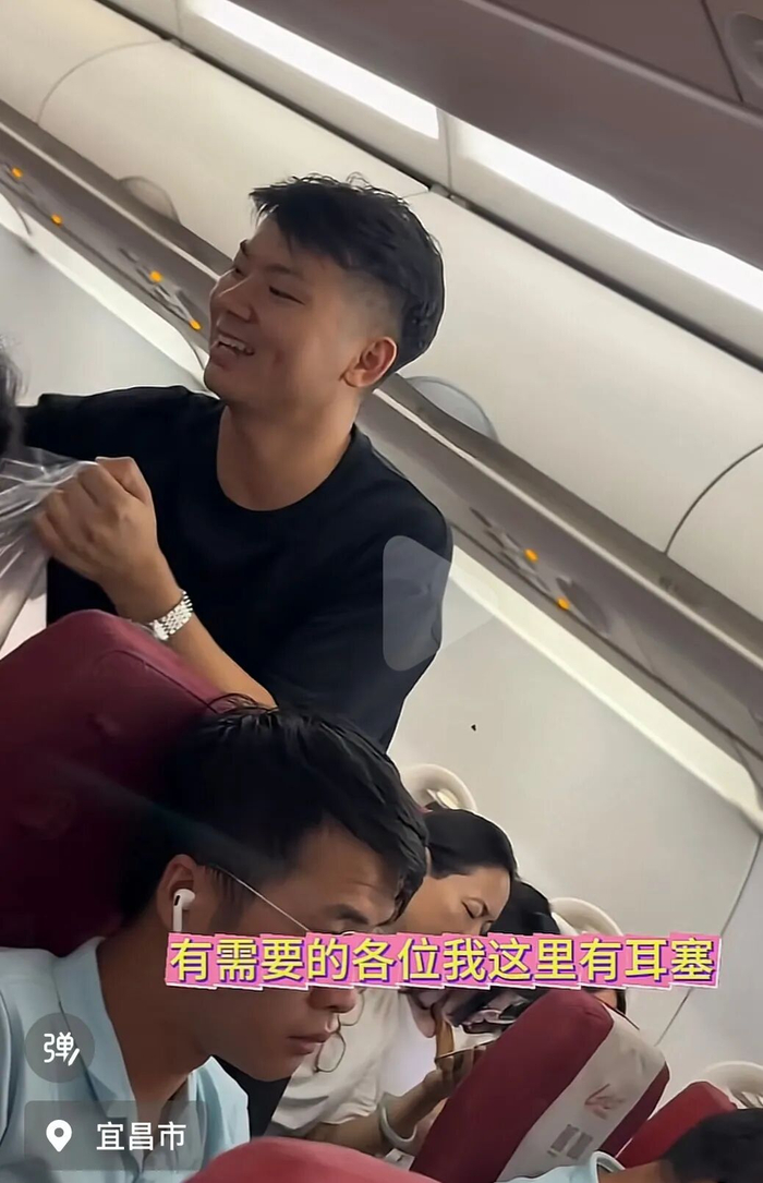 陈先生在机舱内分发耳塞。图/视频截图