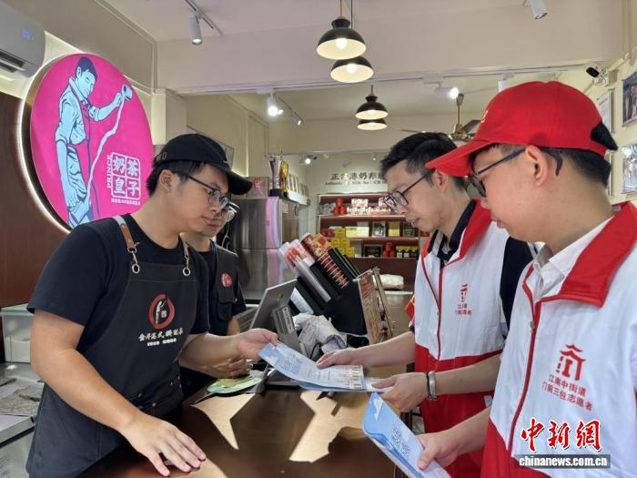 志愿者上门开展“门前三包”宣传。成广聚 摄