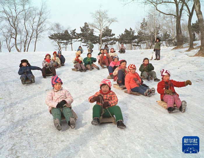 1979年2月7日，吉林市的小学生在雪坡上玩冰爬犁。新华社发