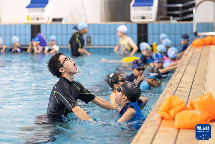 2023年7月21日，教练员在浙江省湖州市游泳馆内指导小朋友换气动作。新华社发（伊凡 摄）