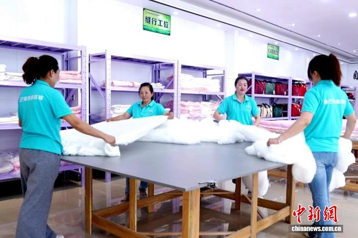 图为陕西省汉中市镇巴县一工厂内，工人们正在整理蚕丝产品。邓先根 摄