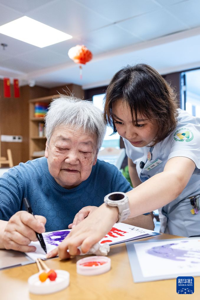 8月17日，沈婉婷（右）指导老人在手工活动上制作DIY纪念品。 新华社发（伊凡 摄）