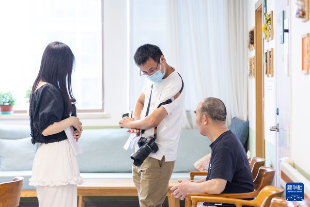 8月11日，主创团队成员孟松（中）在给老人演示表演动作。 新华社发（伊凡 摄）