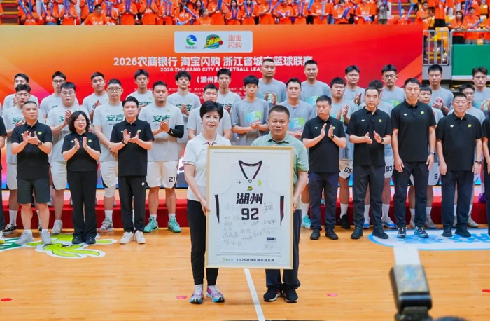▲湖州市体育局局长徐旭萍（左）向德华兔宝宝装饰新材股份有限公司副总经理徐伟达（右）赠送湖州队定制球衣。