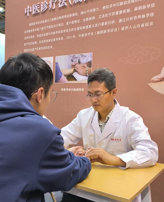 图：贾荣军主任在非物质文化遗产博览会脉诊