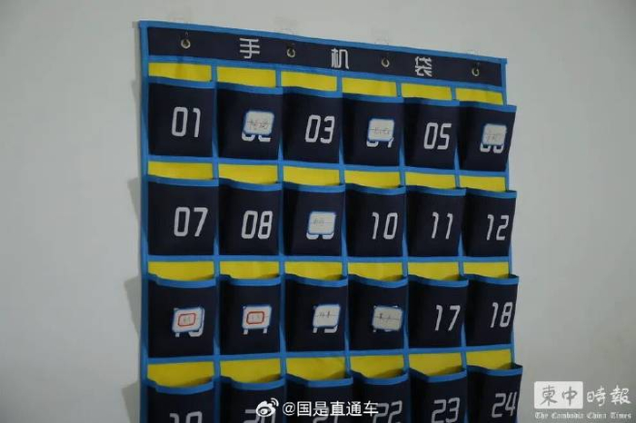 办公区域墙上设置编号“手机袋”，部分位置贴有中文姓名标签。（图：柬中时报）