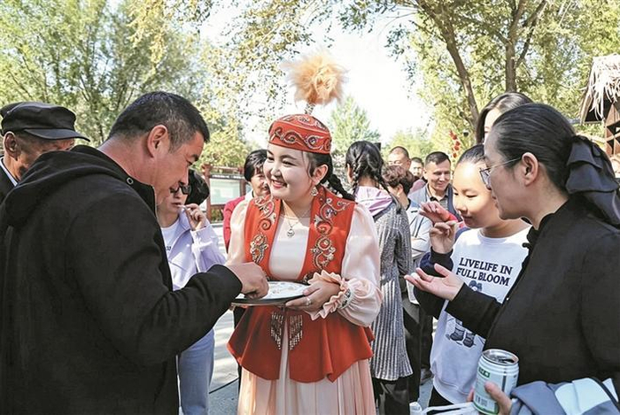    9月2日，在六师红旗农场举办的民族团结主题活动中，工作人员端上特色美食，邀请群众品尝。    郑嘉莉  摄